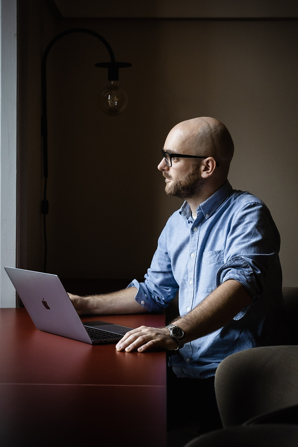 Sebastian working at a laptop by the warm light of a wall lamp