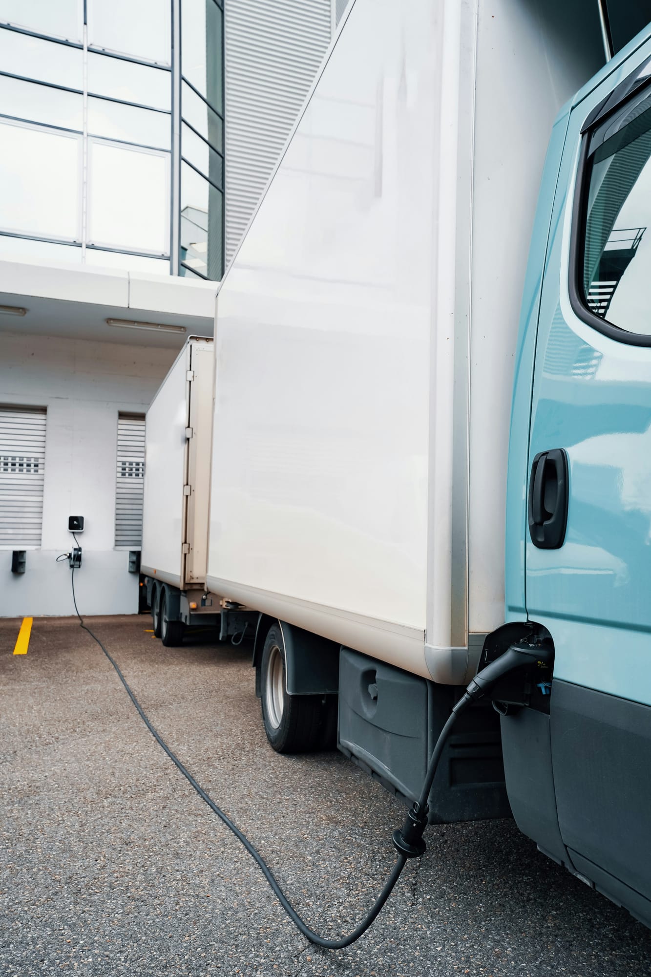 An electric box truck charging at a depot loading bay