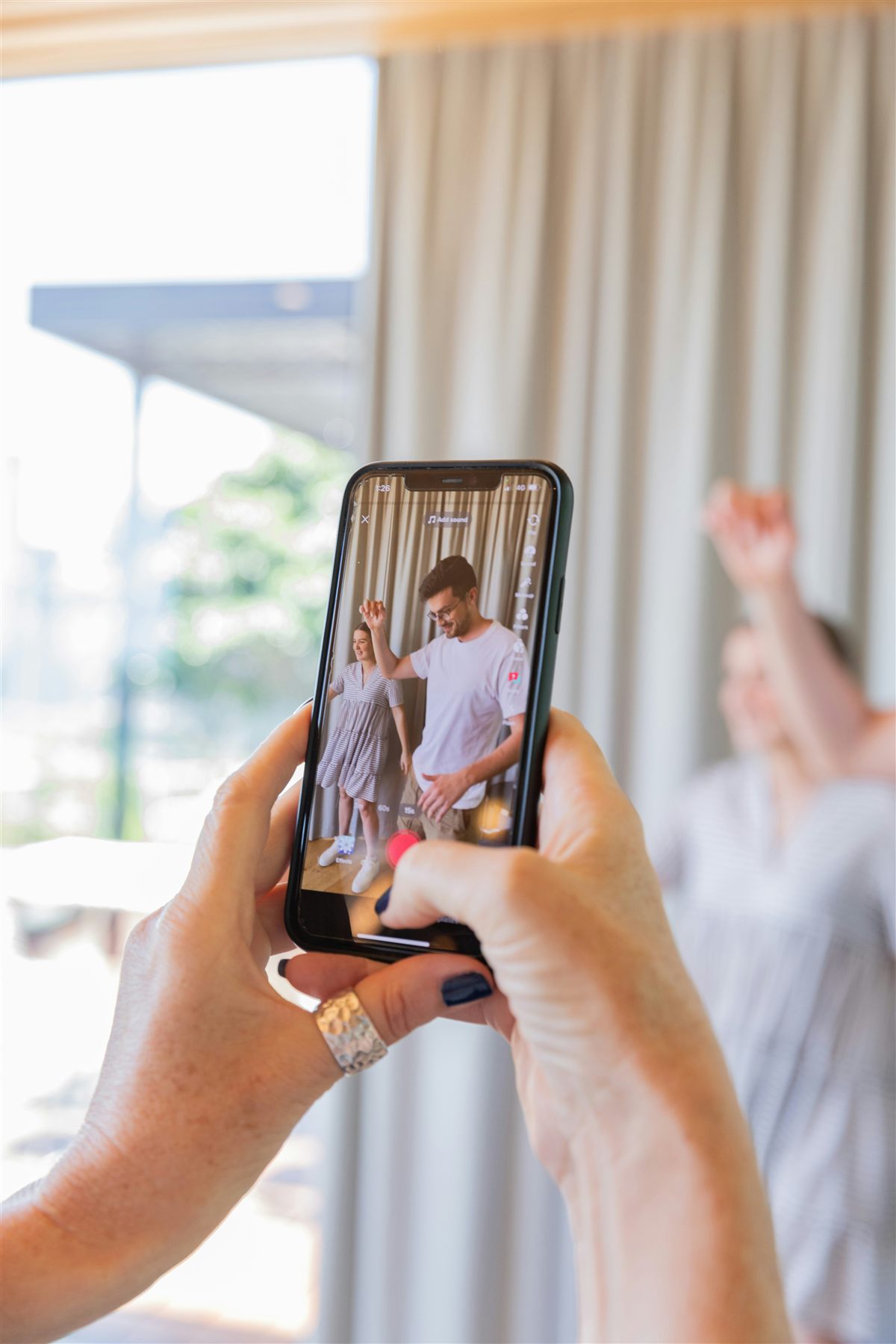 Someone filming friends laughing and dancing in bright daylight on a phone