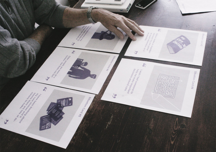 An elderly participant sorting illustrated situation cards on a dark wooden table
