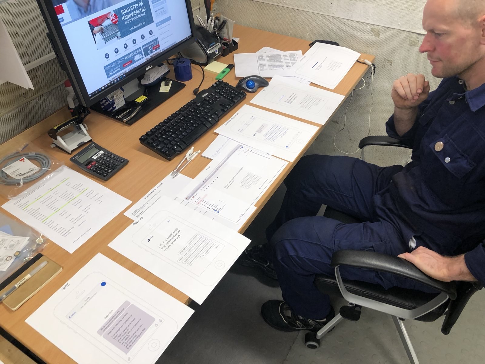 A seafarer at his desk on board, reviewing paper prototypes of the Scoutbase questions