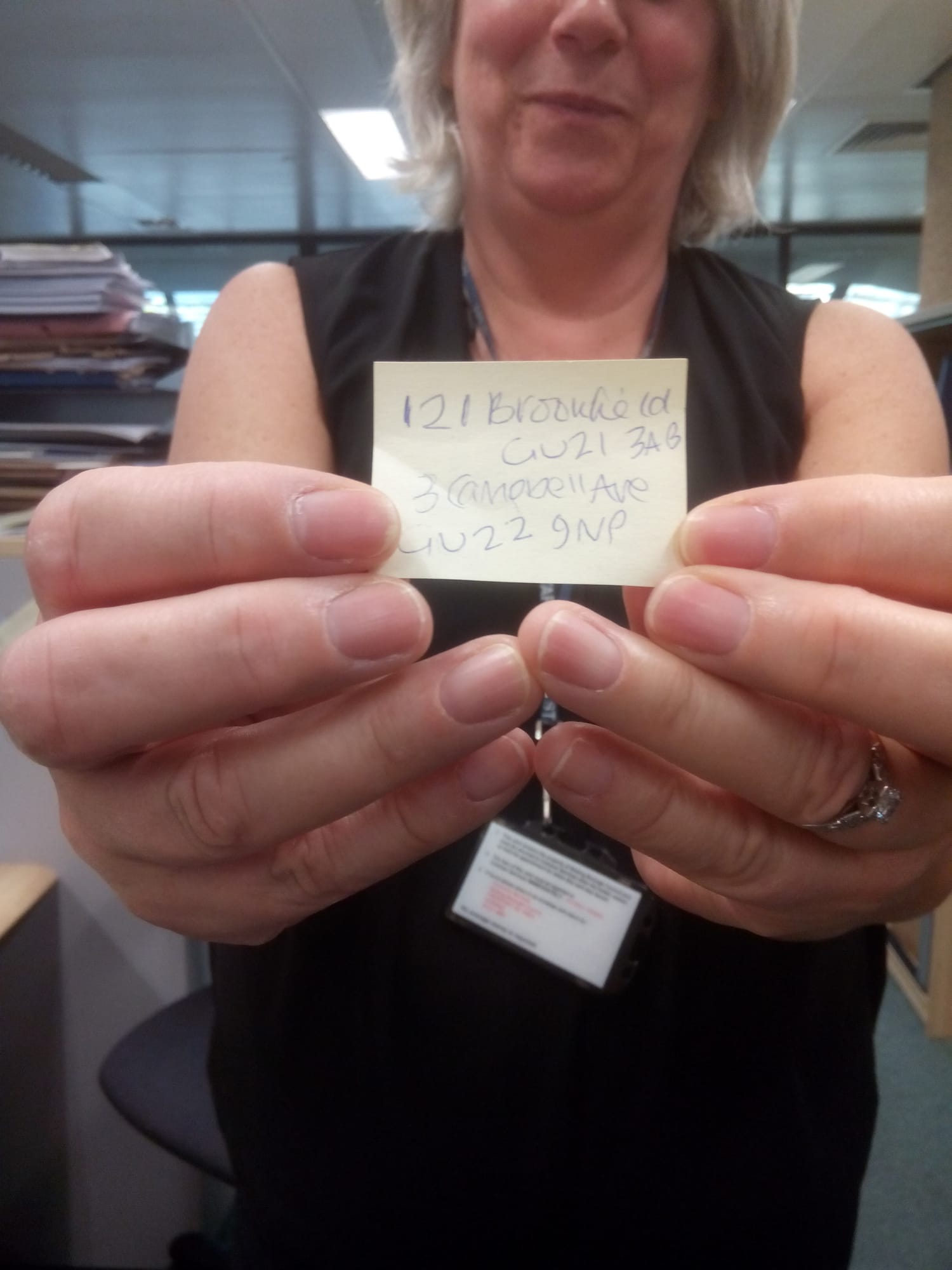 A caseworker holding a Post-it note with two handwritten housing addresses